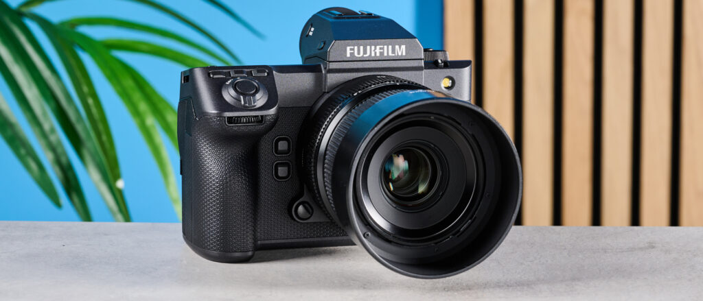 The Fujifilm GFX100 II on a stone surface with a blue background