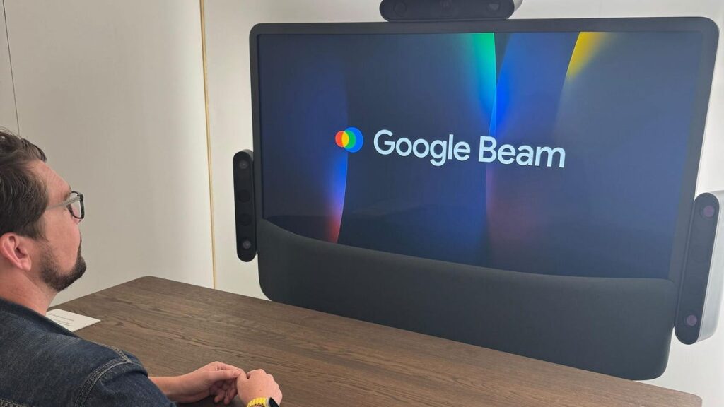 Google Beam Brings More Natural Video Conversations Within Reach A man sits at a desk in front of a large display.