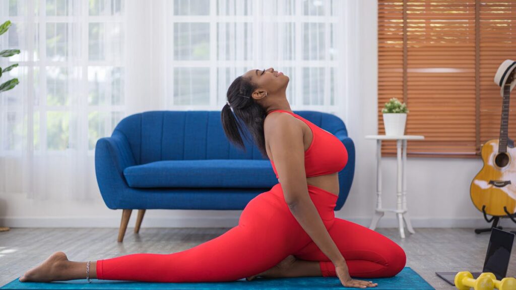 A woman in neon gym clothes is doing a yoga pose in a lounge room.