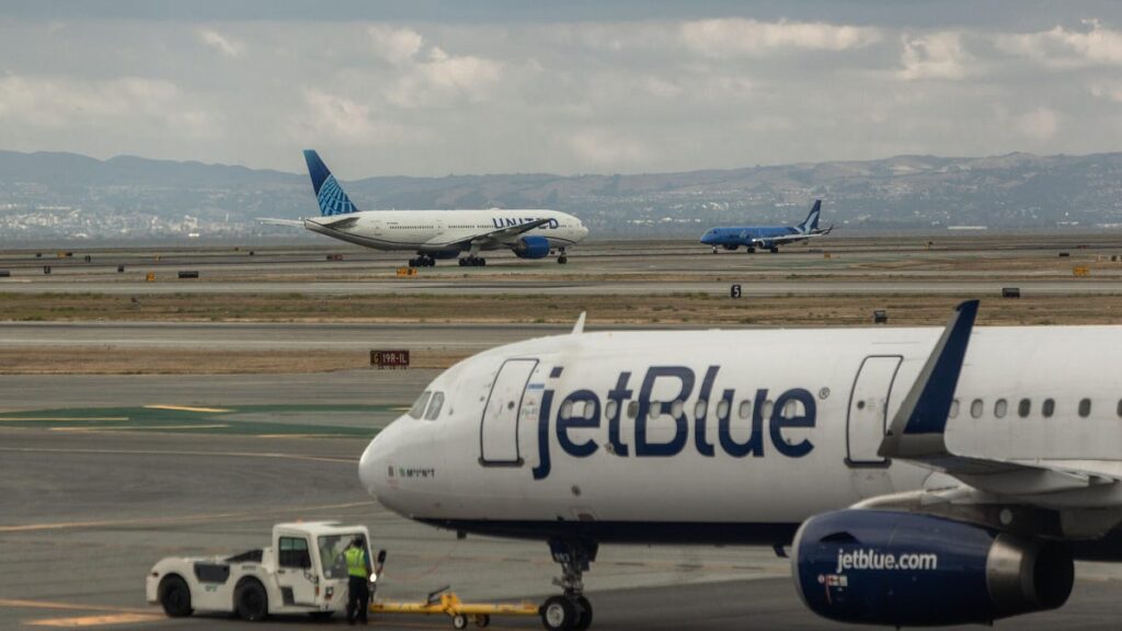 A Jetblue airplane, a United Airlines jet, and a Breeze Airways plane passing at the Airport.