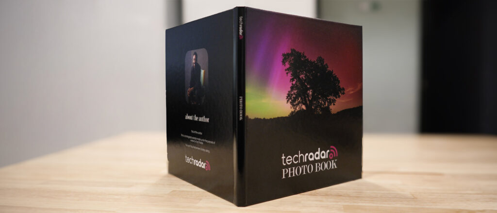 The Printique photo book propped open so you can see the front and rear covers simultaneously; the front image shows an aurora and the words 'TechRadar Photo Book'.