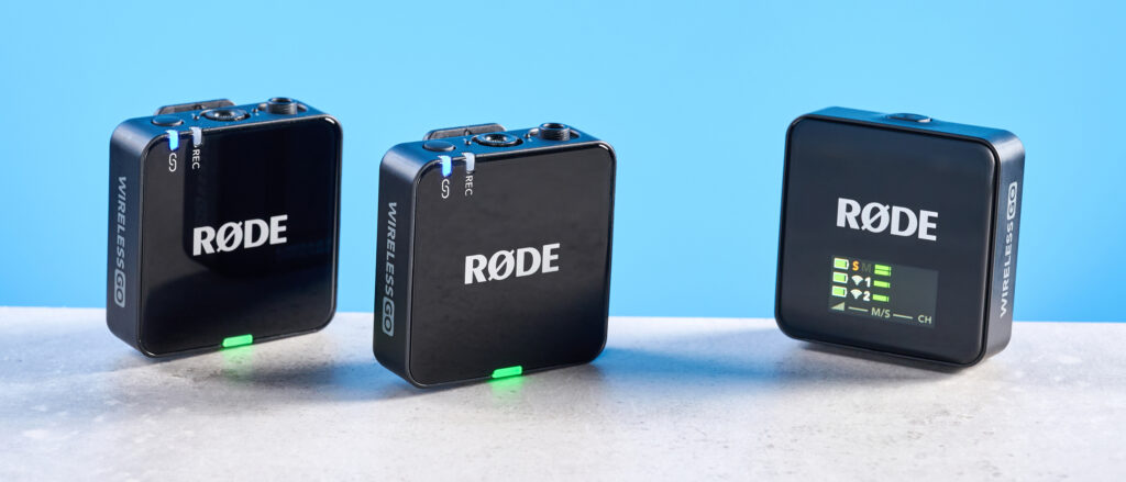 the rode wireless go gen 3 microphone with one receiver, two transmitters, shown against a blue background and with accessories like dead cat, charging ports, and cables