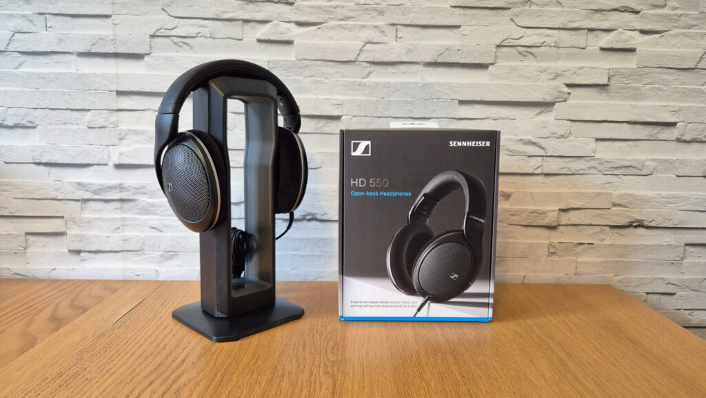 The Sennheiser HD 550 headphones on a wooden surface in front of a white brick background