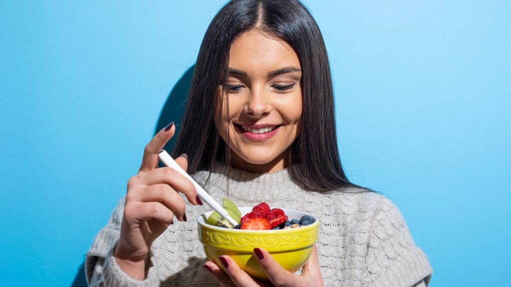 Woman easting bowl with fruits
