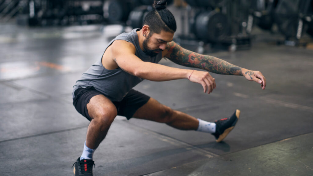 A man performing a bodyweight lower body exercise: cossack squat