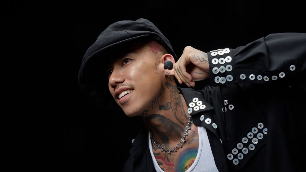 Audio-Technica’s new wireless earbuds have a genuinely mind-blowing upgrade that leaves my AirPods feeling utterly inadequate A young man with neck tattoos wearing a white top and black jacket is also wearing Audio-Technica ATH-CKS50TW2 earbuds and a black hat. He is photographed on a black background