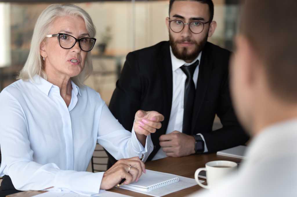 CISOs reposition their roles for business leadership Negotiations lead by middle-aged boss talking with client diverse business people gathered together at boardroom, job interview process european and arabian HR managers interweaving applicant concept