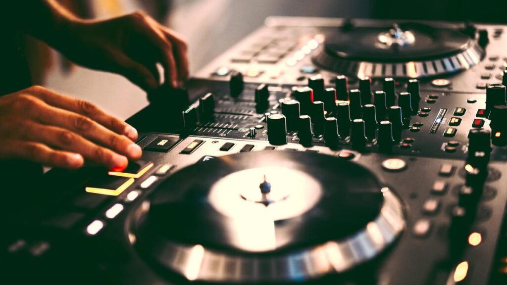 A closeup of a DJ mixing table with a DJ&apos;s hands on the controls. gettyimages-2194731676