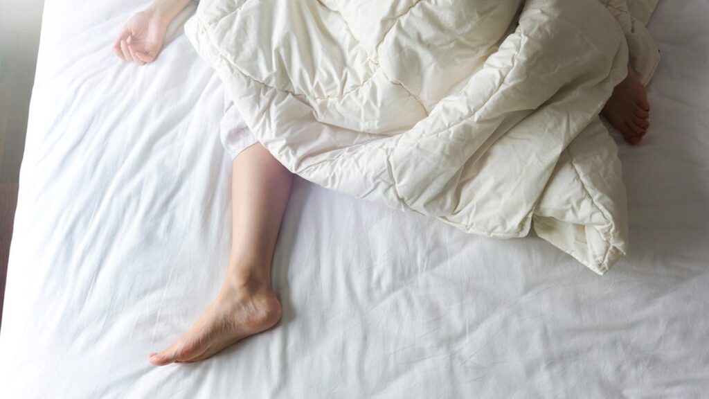 Person lies down on white bed