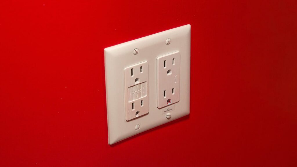 Save Up to $100 on Your Electric Bill by Unplugging These Devices Home electrical outlet with four plugs, in a red wall