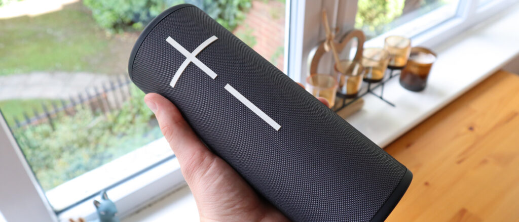 Ultimate Ears Megaboom 4 held in a hand, in front of a window