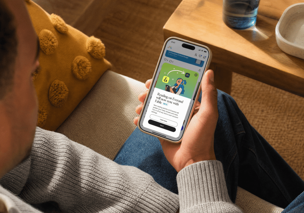 A startup, Everand, is now bundling e-books, audiobooks, and book clubs in challenge to Amazon person looking at Everand app on smartphone